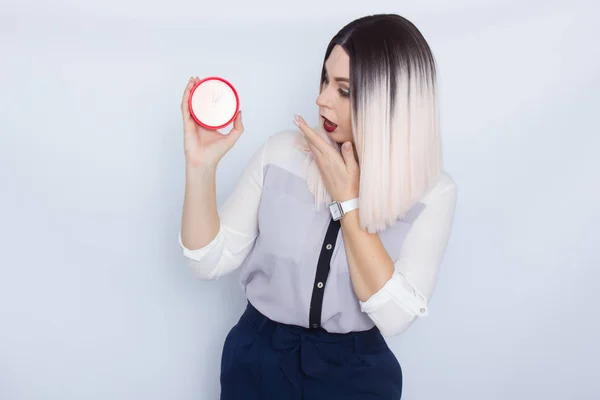 Mulher loira segurando despertador vermelho em suas mãos — Fotografia de Stock