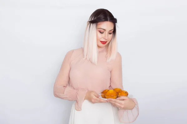 Blond kobieta trzyma ciasta na białej płycie — Zdjęcie stockowe