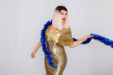 Gece altın elbise ve boynunda tinsel ile duygusal mutlu sarışın kadın.