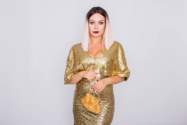 Zarif altın gece elbisesi giyen ve elinde altın renk debriyaj tutan Büyüleyici genç sarı saçlı kadın