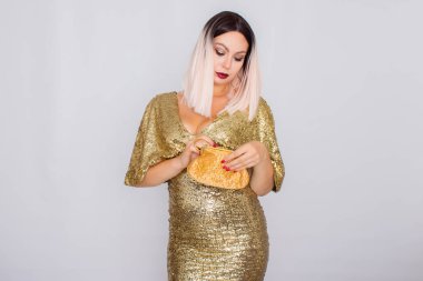 Zarif altın gece elbisesi giyen ve elinde altın renk debriyaj tutan Büyüleyici genç sarı saçlı kadın