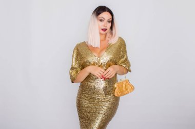 Zarif altın gece elbisesi giyen ve elinde altın renk debriyaj tutan Büyüleyici genç sarı saçlı kadın