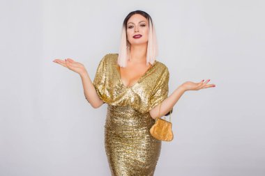 Zarif altın gece elbisesi giyen ve elinde altın renk debriyaj tutan Büyüleyici genç sarı saçlı kadın