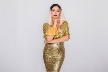 Zarif altın gece elbisesi giyen ve elinde altın renk debriyaj tutan Büyüleyici genç sarı saçlı kadın