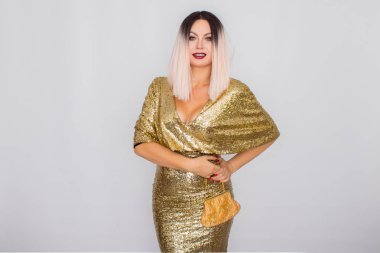 Zarif altın gece elbisesi giyen ve elinde altın renk debriyaj tutan Büyüleyici genç sarı saçlı kadın