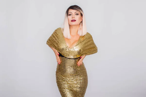 Porträt einer schönen Blondine mit hellem Make-up in einem goldenen Kleid — Stockfoto