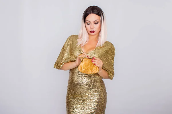 Charmante junge blondhaarige Frau trägt elegantes goldenes Abendkleid und hält goldfarbene Clutch in ihren Händen — Stockfoto