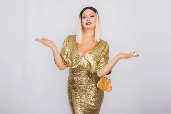 Encantador jovem loira cabelo mulher vestindo elegante vestido de noite de ouro e segurando embreagem cor de ouro em suas mãos — Fotografia de Stock