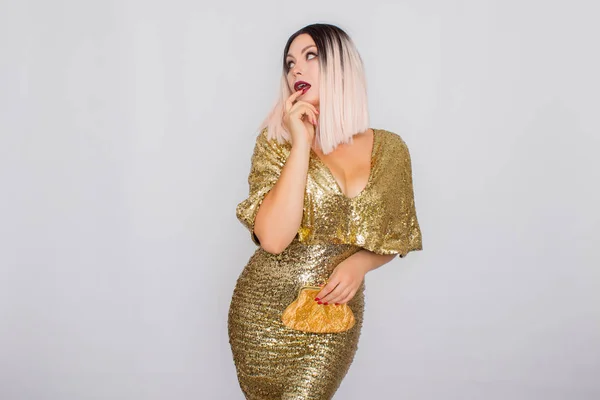 Encantador jovem loira cabelo mulher vestindo elegante vestido de noite de ouro e segurando embreagem cor de ouro em suas mãos — Fotografia de Stock