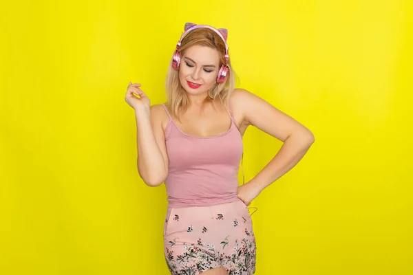 穿着粉色夏装 戴着粉色耳机 像小猫耳朵的金发女人 — 图库照片