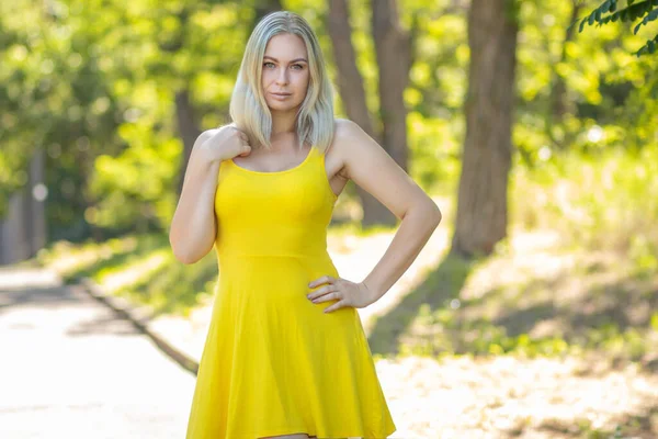 黄色のショートドレス 夏のファッション衣装 公園でカクテルを飲む魅力的なスタイリッシュなブロンドの笑顔の女性 — ストック写真