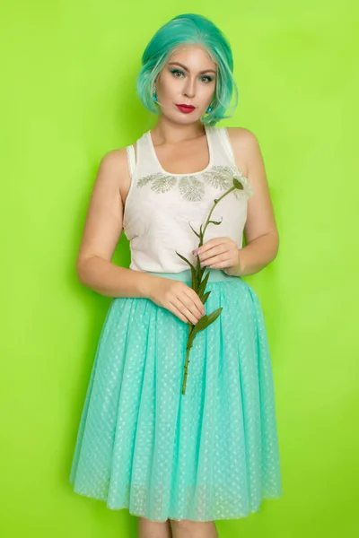 工作室的肖像 美丽的薄荷色头发 白色上衣 浅蓝色裙子 手里拿着大洋甘菊 绿色背景 — 图库照片