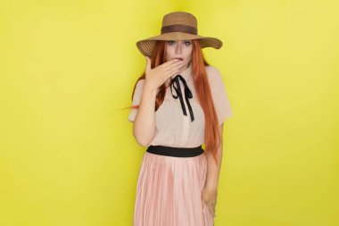 Sarı arka plan, stüdyo, tarz, yaz konsepti üzerinde hasır şapkalı kızıl saçlı kadın.