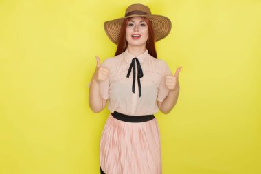 Sarı arka plan, stüdyo, tarz, yaz konsepti üzerinde hasır şapkalı kızıl saçlı kadın.