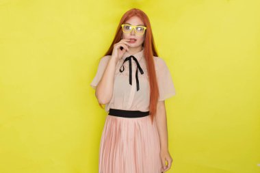Sarı arka plan, stüdyo, tarz, gözlüklü ve ofis elbiseli kızıl saçlı kadın.