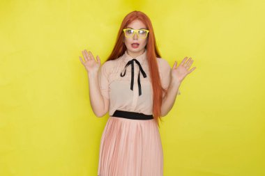 Sarı arka plan, stüdyo, tarz, gözlüklü ve ofis elbiseli kızıl saçlı kadın.