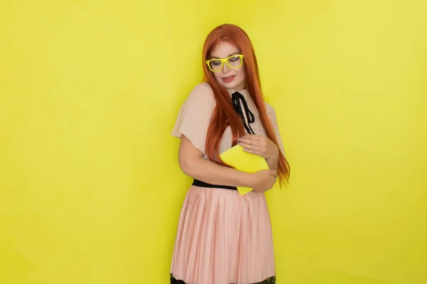 赤い毛の女性上に黄色の背景保持本で彼女の手 スタジオショット モデルポーズ — ストック写真