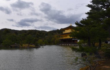 Zen Budist Tapınağı Kinkaku-ji çarpık çam ormanları arasında parıldayan altın katlarıyla Japonya 'nın Kyoto Gölü' ne yansıyor.
