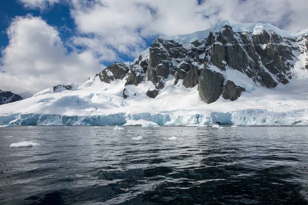 icecaps in the Antarctica with iceberg in the ocean swimming around and melting in the sea