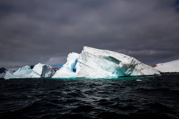 icecaps in the Antarctica with iceberg in the ocean swimming around and melting in the sea