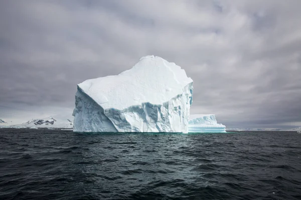 icecaps in the Antarctica with iceberg in the ocean swimming around and melting in the sea