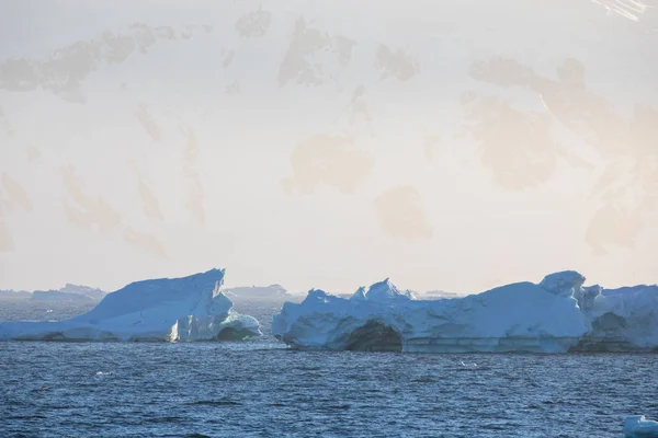 icecaps in the Antarctica with iceberg in the ocean swimming around and melting in the sea