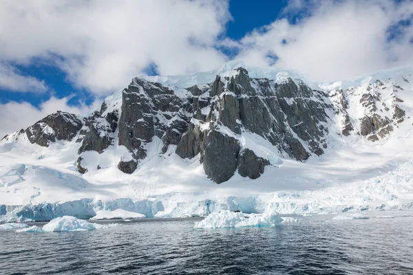 icecaps in the Antarctica with iceberg in the ocean swimming around and melting in the sea