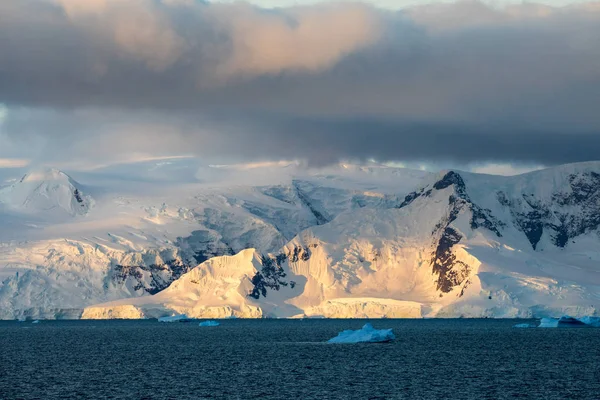 icecaps in the Antarctica with iceberg in the ocean swimming around and melting in the sea