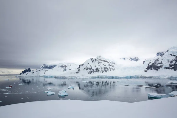 icecaps in the Antarctica with iceberg in the ocean swimming around and melting in the sea