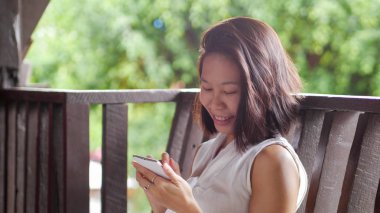 Doğal doğa bahçe arka planda cep telefonu mutlu gülümseme kullanarak Asyalı kadın