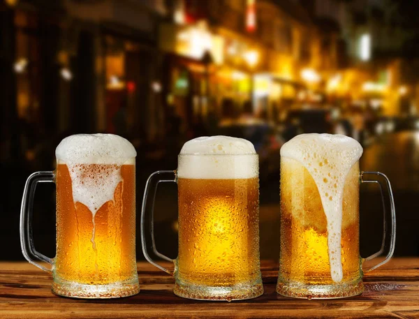 街の背景に泡とビールの冷たいガラス マグカップ — ストック写真