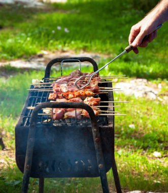 Pişirme adam Türkiye şaşlık ahşap şiş ızgara üzerinde Marine. Arka bahçede parti arka plan.