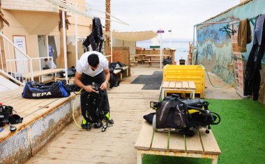 Eilat, İsrail - 22 Şubat 2016: Adam Coral Beach Doğa Koruma Alanı'nda dalış yapmadan önce ekipmanLarını kontrol ediyor. Bu dünyanın en güzel mercan resifi biri ünlü turistik ve dalgıç cazibe olduğunu.