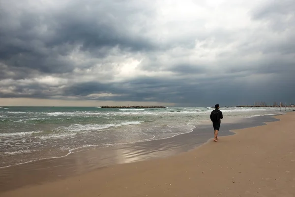 Młody Mężczyzna Nierozpoznany Widok Tyłu Spacerujący Boso Wzdłuż Plaży Pochmurny Zdjęcie Stockowe