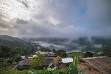 Sabah yoğun bulutlar ve sis kaplı. İnsanlar güzel turist çeken bir dağın tepesinde gündoğumu bakıyor