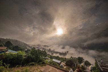 Sabah yoğun bulutlar ve sis kaplı. İnsanlar güzel turist çeken bir dağın tepesinde gündoğumu bakıyor