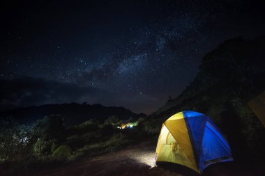 Yıldızlı gökyüzünün altındaki dağlarda parlayan çadır 