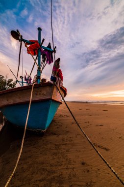 Bir çakıl üzerinde eski bir ahşap balıkçı teknesi üzerinde güzel gündoğumu