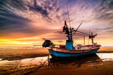 Bir çakıl üzerinde eski bir ahşap balıkçı teknesi üzerinde güzel gündoğumu