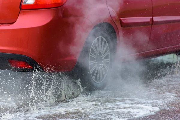 자동차에 빗발치는 물보라가 바퀴에서 쏟아진다 — 스톡 사진