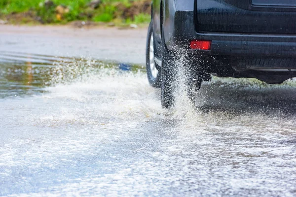 汽车运动雨水从车轮上喷出一大团水花 — 图库照片