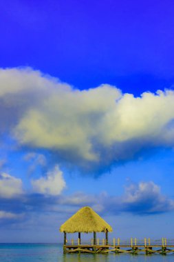 Tropikal beyaz kumlu plaj. Palmiye yaprağı çatılı ahşap iskele sahilde gazebo ile. La Romana, Dominik Cumhuriyeti. 