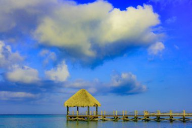 Tropikal beyaz kumlu plaj. Palmiye yaprağı çatılı ahşap iskele sahilde gazebo ile. La Romana, Dominik Cumhuriyeti. 