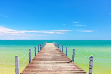 wooden batten bridge juts out into the expanse of the sea clipart