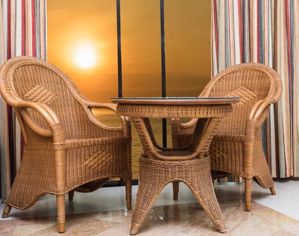 sunset view from the window of a hotel room in a resort with wicker rattan furniture