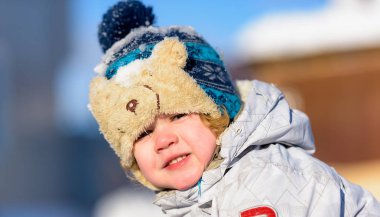 Karda oynarken bir yastıklı ceket ve örgü şapka giyen eğleniyor portre küçük çocuk çocuk.