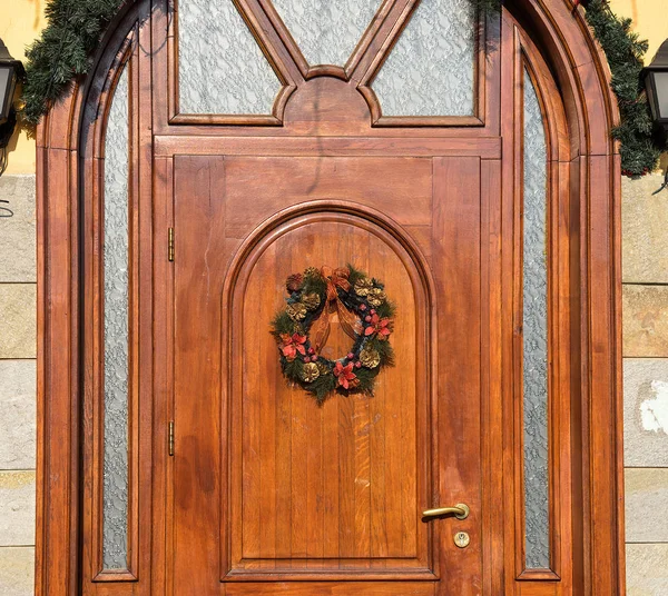 Drewniane drzwi ozdobione świątecznym wieńcem — Zdjęcie stockowe