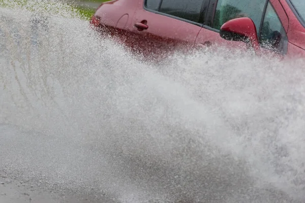 汽车运动雨水从车轮上喷出一大团水花 — 图库照片