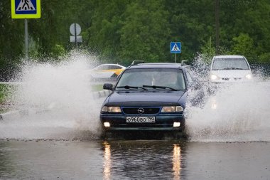 - Rusya. Moskova. 30 Mayıs 2020. Bir araba su birikintisinin içinden su sıçratarak geçiyor. Şehirde bahar seli.