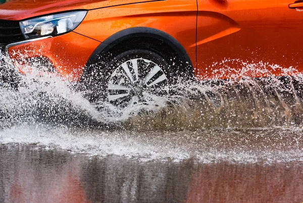 자동차에 빗발치는 물보라가 바퀴에서 쏟아진다 스톡 사진
